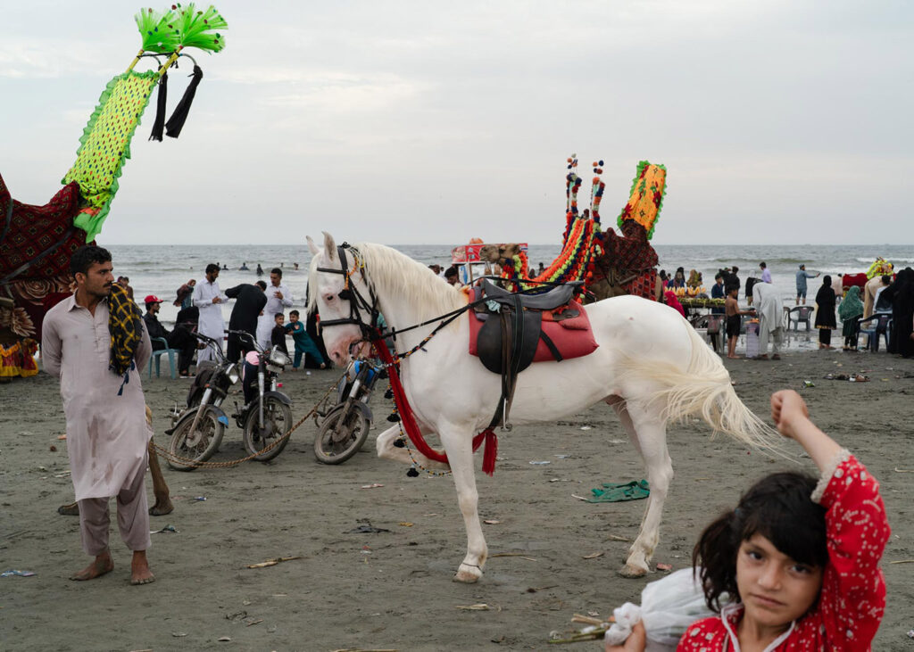 Essere donna in Pakistan - Una bambina vende fiori a Clifton Sea View, la spiaggia più famosa di Karachi. Clifton Sea View è uno dei pochi luoghi in città dove le persone di ogni estrazione sociale possono stare assieme, fare il bagno e passeggiare. Karachi, Pakistan, 16 aprile 2024.