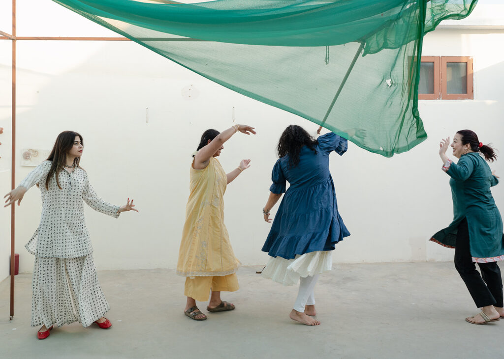 Essere donna in Pakistan - Le amiche della futura sposa, Sharmeen, ballano durante i preparativi per il matrimonio su un tetto affittato per l'occasione. La cerimonia che precede il matrimonio, a cui lo sposo non può partecipare e che viene celebrata con le amiche e i genitori della sposa, si chiama "Dholki". Il nome deriva dallo strumento a percussione Dholki, ed è una parte importante delle celebrazioni nuziali nel Punjab e nella Divisione Hazara di Khyber Pakhtoon Khwa. Tradizionalmente, molti giorni o persino settimane prima del matrimonio, le donne si riuniscono a casa della sposa di notte per cantare e ballare, accompagnate da altri strumenti a percussione. Karachi, Pakistan, 11 aprile 2024.